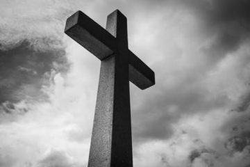 Black and white cross with clouds in background